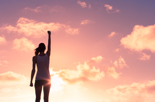 Silhouette of woman in victory stance for staying sober and on track.